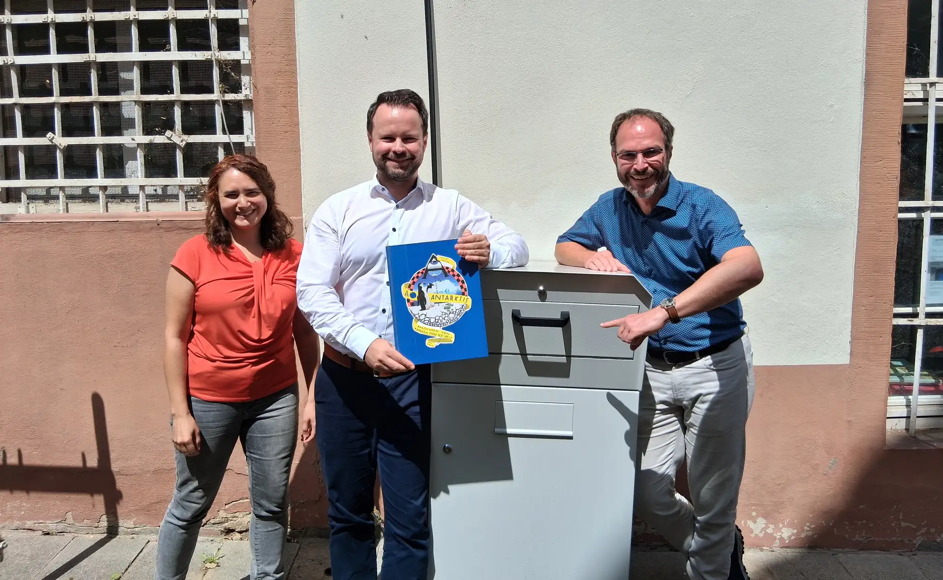 Eine graue Medien-Rückgabebox mit Einwurfklappen für Bücher und für digitale Medien wie Tonies.