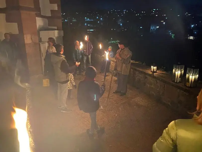 Stimmungsvoller Blick auf eine historische Altstadt bei Nacht mit Fackeln.